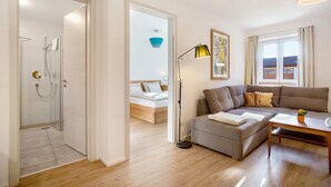 A modern living room with a sofa, a coffee table, a floor lamp, and a bed with a view. - Apartment 4 – Well-Equipped Kitchen, Spacious Outdoor Area, and Beautiful Nature Views (Kirchseeon)