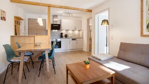 A modern kitchen with white cabinets, a dining table with chairs, and a sofa in a living area. - Apartment 4 – Well-Equipped Kitchen, Spacious Outdoor Area, and Beautiful Nature Views (Kirchseeon)