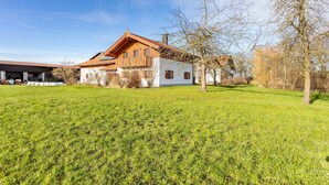 A traditional chalet-style house with a sloped roof, wooden exterior, and a large grassy yard. - Apartment 10 – Two-Level Living with Separate Bedroom and Well-Equipped Kitchen (Kirchseeon)