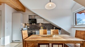 A modern kitchen with a marble countertop, wooden cabinets, and a dining area with a wooden table and chairs. - Apartment 10 – Two-Level Living with Separate Bedroom and Well-Equipped Kitchen (Kirchseeon)