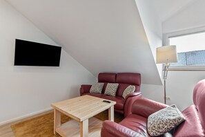 A modern living room with a sofa, a coffee table, a TV mounted on the wall, and a lamp.