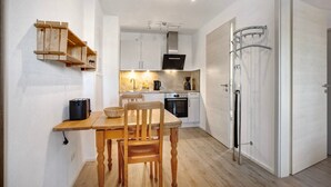A compact kitchen with wooden shelves, a dining table, and a modern oven. - Apartment 1 – Well-Equipped Kitchen, Spacious Outdoor Area, and Lovely Nature Views (Kirchseeon)