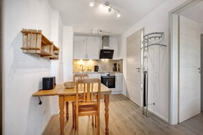A compact kitchen with wooden shelves, a dining table, and a modern oven.