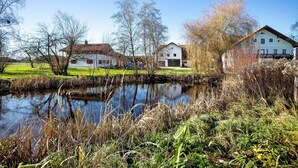 Um cenário tranquilo à beira de um lago, com edifícios tradicionais, um lago calmo e vegetação exuberante.