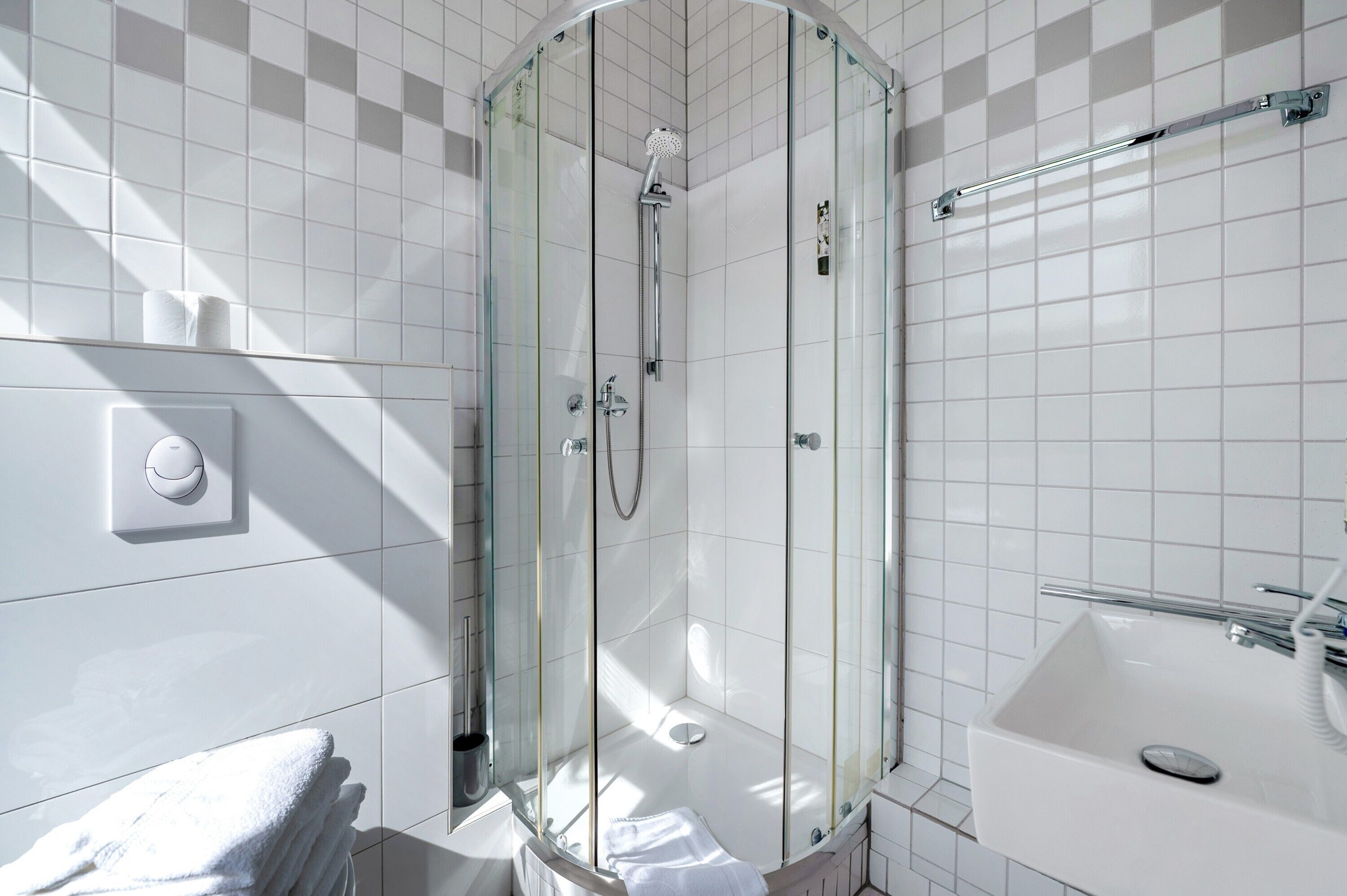 A modern bathroom with a glass-enclosed shower, a white sink, and a towel rack.