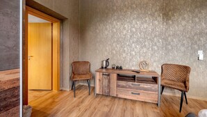Una habitación con un escritorio de madera, dos sillas, una puerta y una pared con textura.
