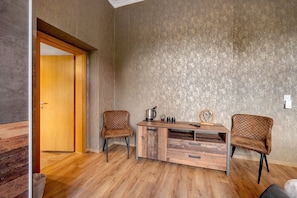 A room with a wooden desk, two chairs, a door, and a textured wall.