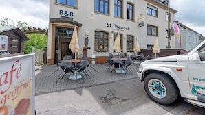 A building with a sign reading 'B&B St. Wendel' and outdoor seating with umbrellas. - Room 'Zimmer 2' with Wi-Fi (Prüm)