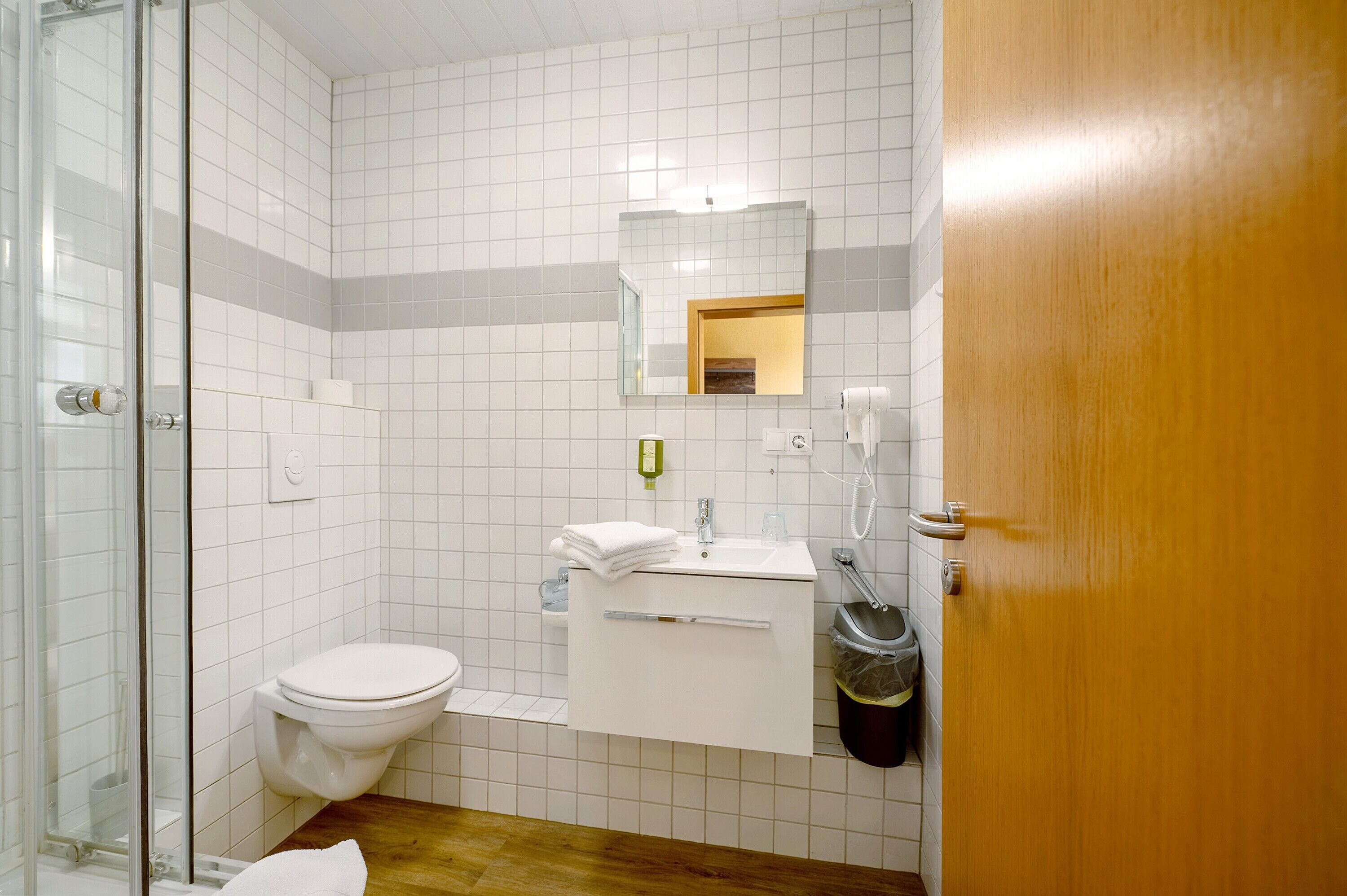 A bathroom with a toilet, sink, mirror, and shower area.