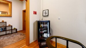 Un couloir avec un distributeur automatique, un miroir et un tableau encadré accroché au mur.