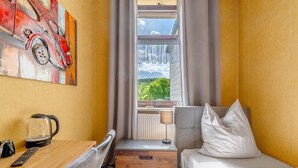 A hotel room with a bed, a desk with a kettle, a lamp, and a painting on the wall. - Room 'Zimmer 4' with Wi-Fi (Prüm)