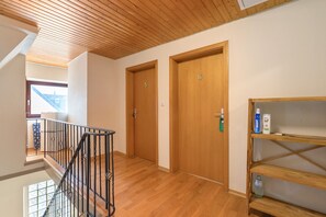 A hallway with wooden doors numbered 5 and 6, a metal railing, and a shelf with toiletries. - Room 'Zimmer 6' with Wi-Fi (Prüm)
