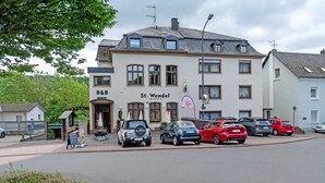 A building with a sign 'St. Wendel cafe und bistro' and a parking area with cars. - Room 'Zimmer 6' with Wi-Fi (Prüm)