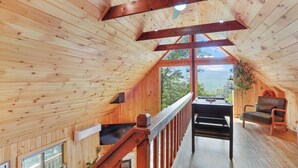 Uma cabana de madeira com quarto no mezanino, área de refeições e vista para o exterior.