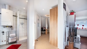 Une salle de bain moderne avec une douche en verre, des toilettes blanches et un porte-serviettes.