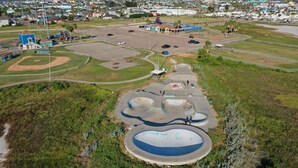 Un parque con varias instalaciones deportivas, incluyendo un campo de béisbol, canchas de baloncesto y una pista de skate.