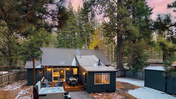 A cabin with a patio, a hot tub, and a deck.