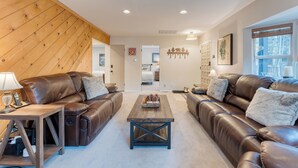 A modern living room with two brown leather sofas, a wooden coffee table, and a wooden accent wall.