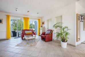 Un salón amplio con un sofá rojo, una mesa de centro y una planta en maceta.