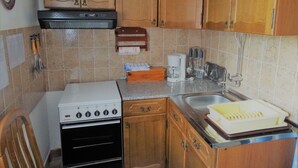 Une cuisine de taille réduite, dotée de meubles en bois, d’une cuisinière, d’un évier et d’appareils électroménagers de base.