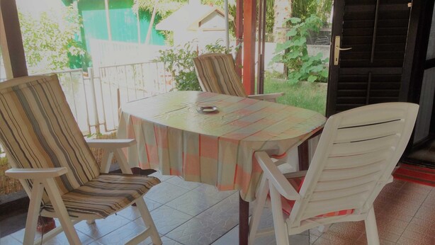 Une table ronde recouverte d’une nappe à carreaux, entourée de quatre chaises à rayures.