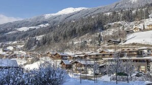 A snow-covered mountain village with wooden buildings and a clear blue sky.