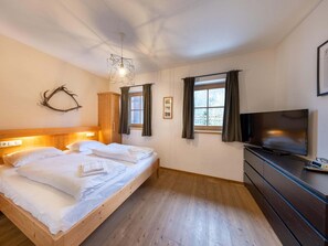 Ein Schlafzimmer mit einem hölzernen Bett, einem Fernseher und einem Fenster mit Vorhängen.