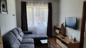 A modern living room with a sectional sofa, a small table, a TV, and a wooden cabinet. - Family-friendly Apartment Crikvenica (Crikvenica)