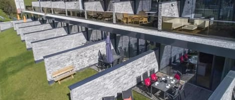 Un edificio moderno con varios niveles, zonas de estar al aire libre y vistas del paisaje circundante.