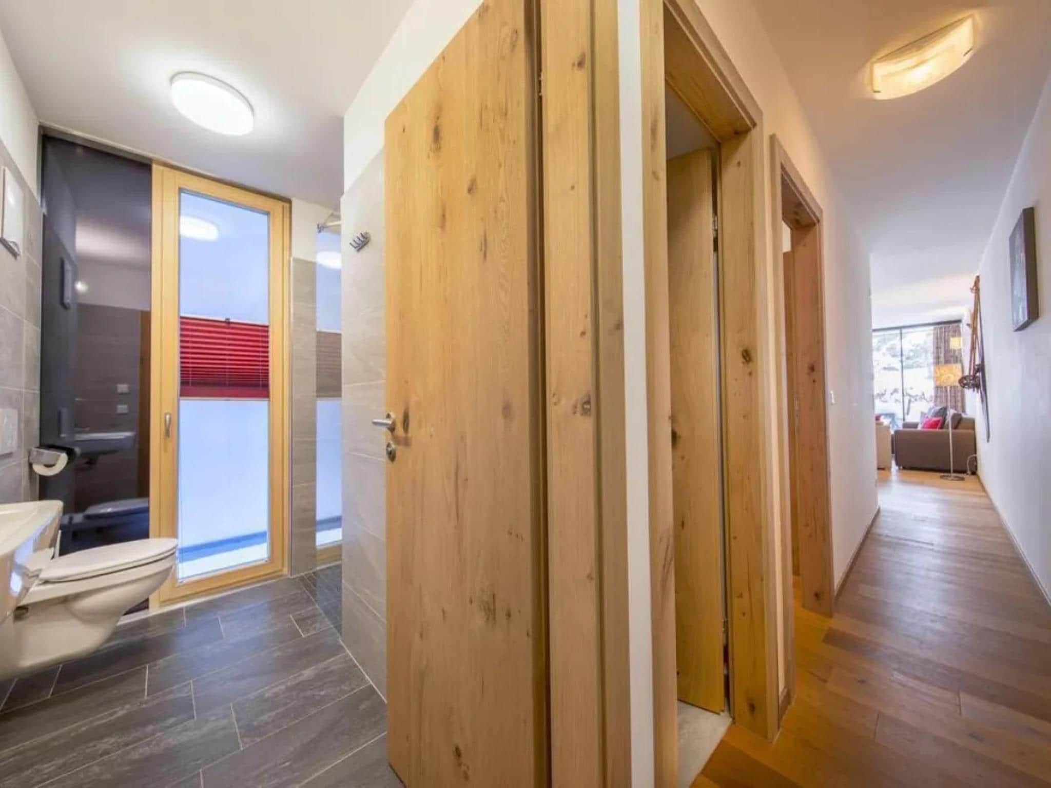 Une salle de bain moderne équipée de toilettes, d’une douche et d’une porte en verre donnant sur un balcon.