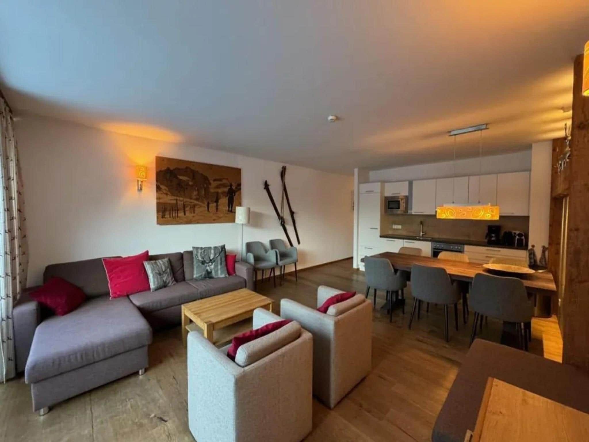 Een moderne woonkamer met een bank, fauteuils en een eethoek met stoelen en een tafel.