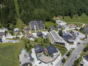 An aerial view of a residential area with multiple apartment buildings, a parking lot, and a road.