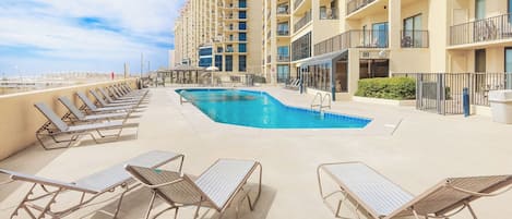 A rooftop pool area with lounge chairs and a swimming pool.