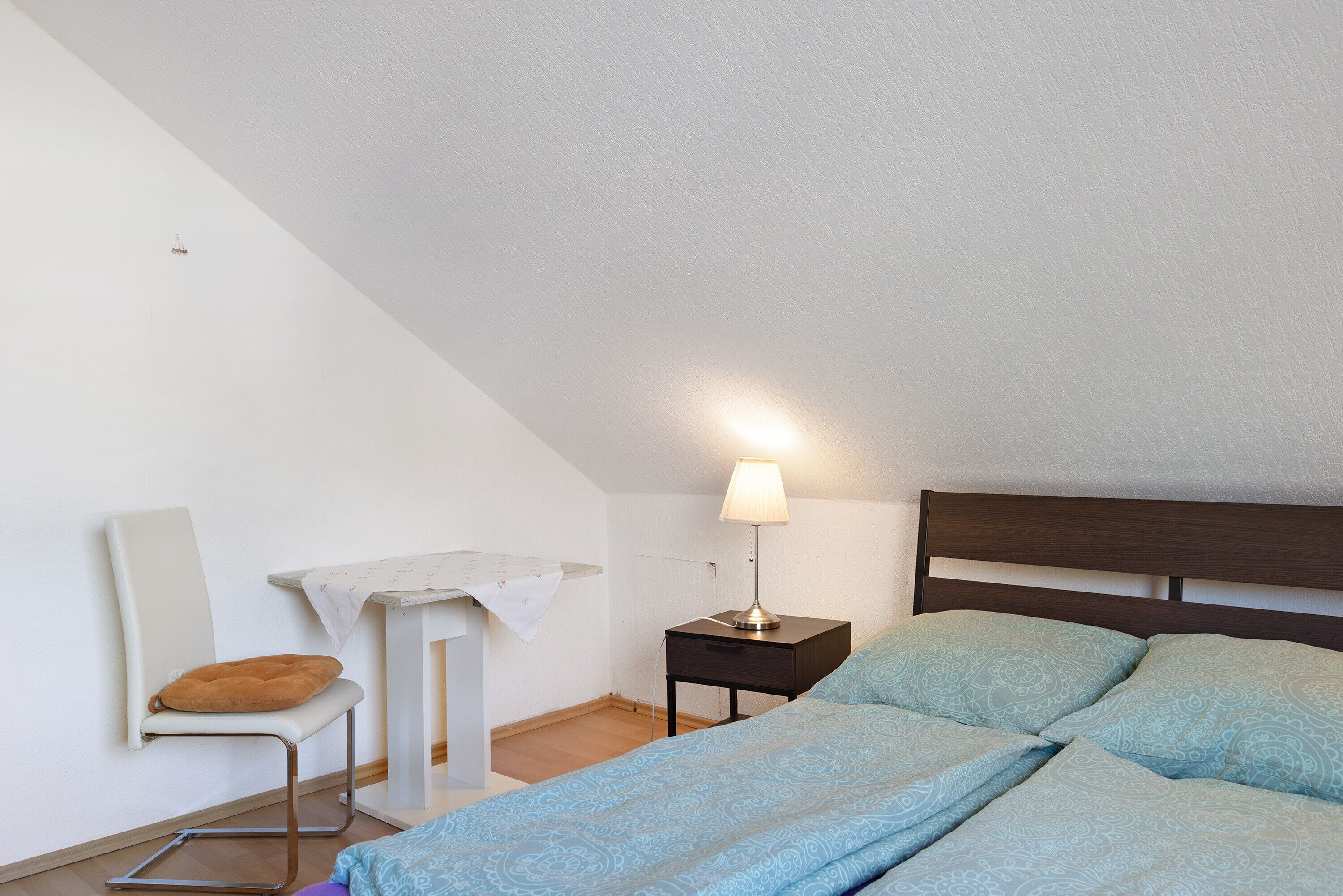 Ein Schlafzimmer mit Bett, Nachttisch, Stuhl und Schreibtisch.