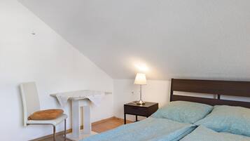 Ein Schlafzimmer mit Bett, Nachttisch, Stuhl und Schreibtisch.