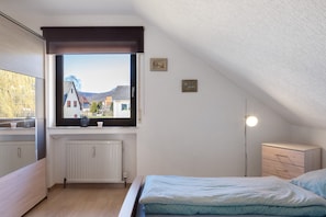A bedroom with a window, radiator, bedside table, lamp, and a bed.