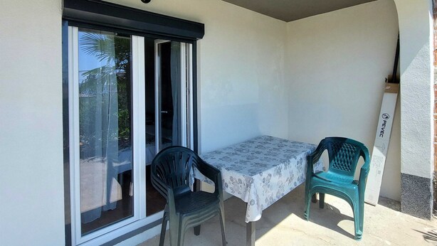 A small balcony with a table and two chairs, a sliding glass door, and a white wall. - Sea View Apartment Crikvenica With Terrace (Crikvenica)