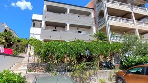 A multi-story building with balconies, a car parked in front, and a staircase leading to the entrance. - Sea View Apartment Crikvenica With Terrace (Crikvenica)