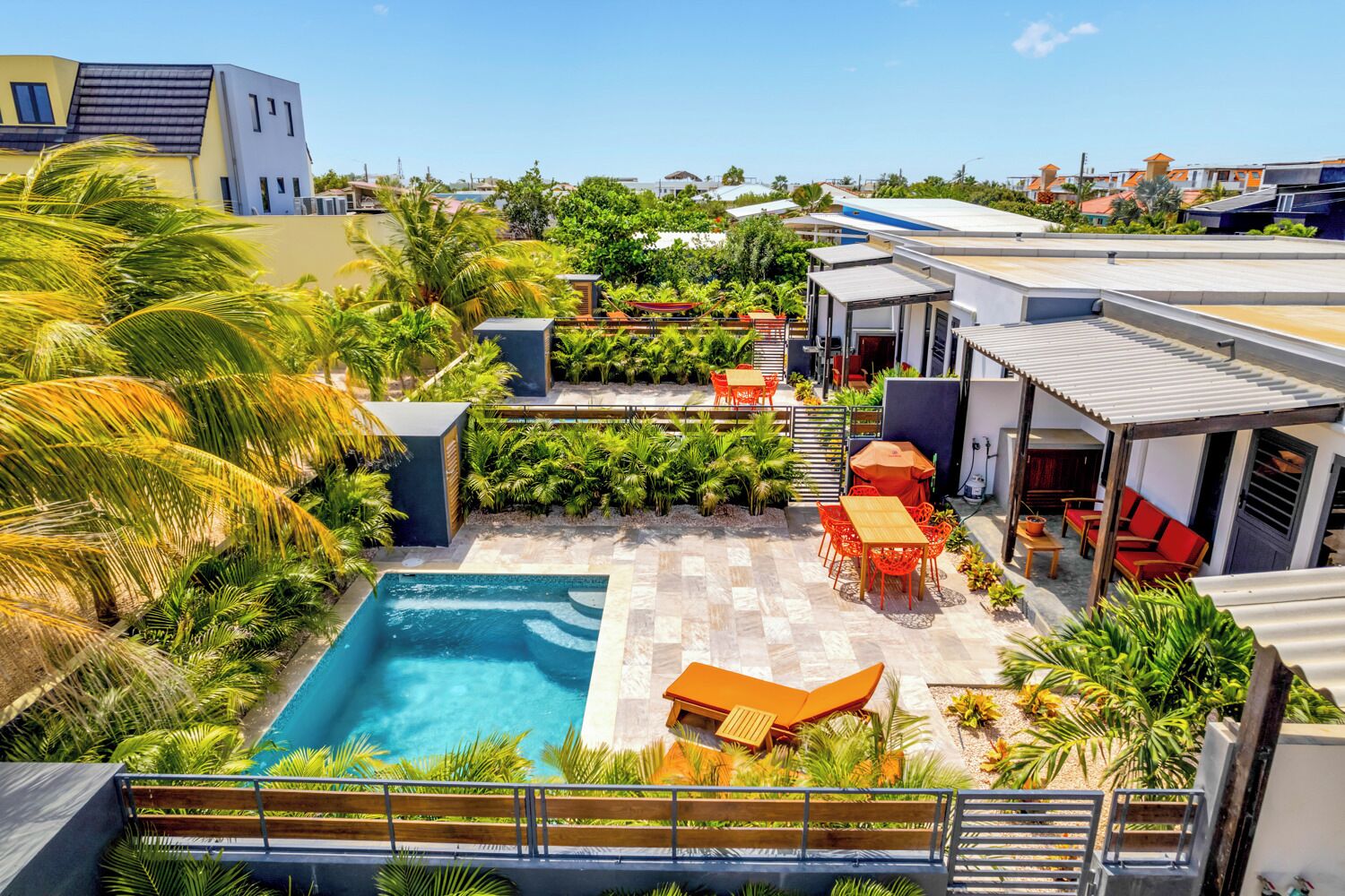 A rooftop pool area with a pool, seating, and surrounding greenery.