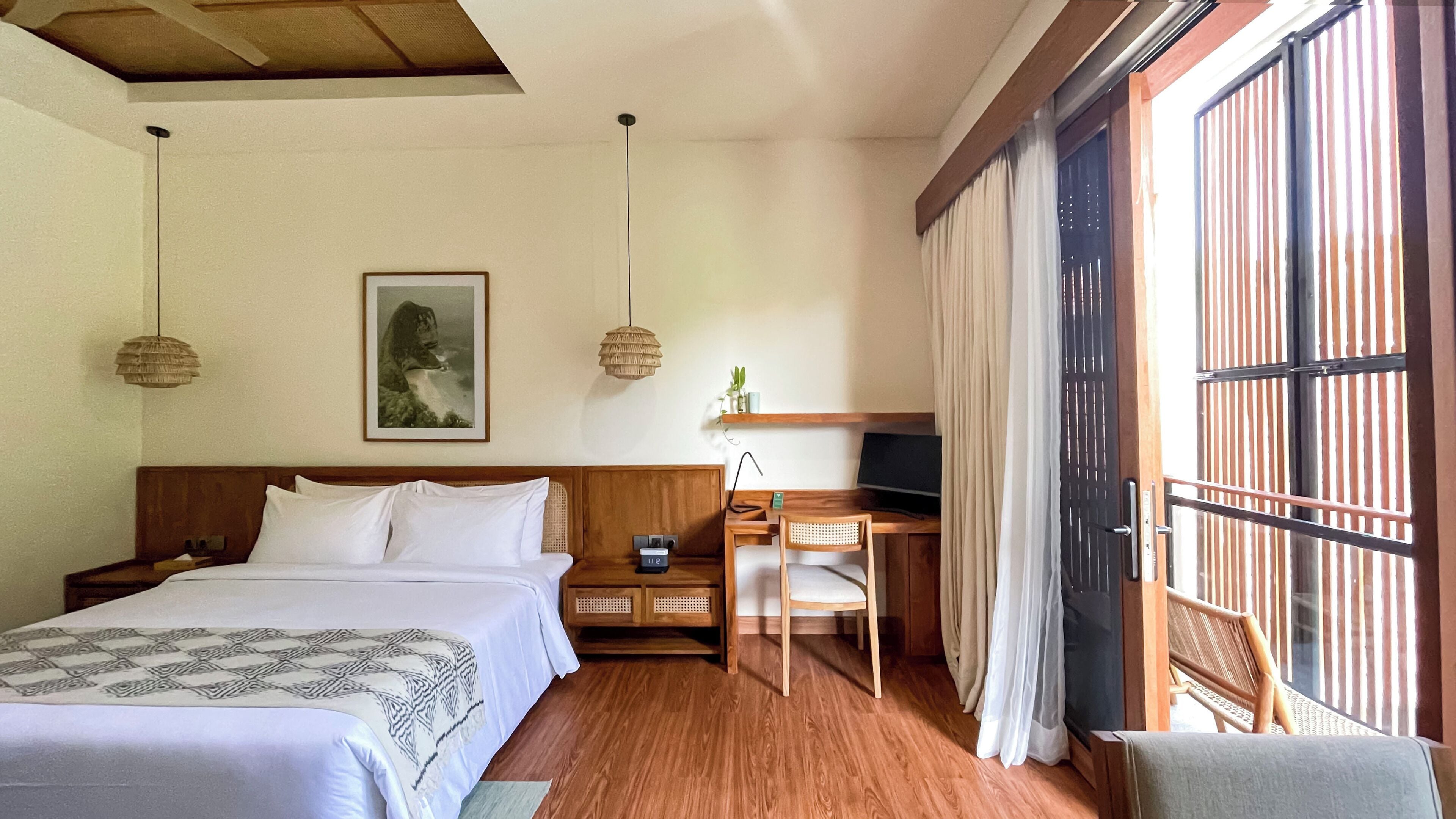 A hotel room with two beds, a desk, a chair, a television, and a large window with curtains.