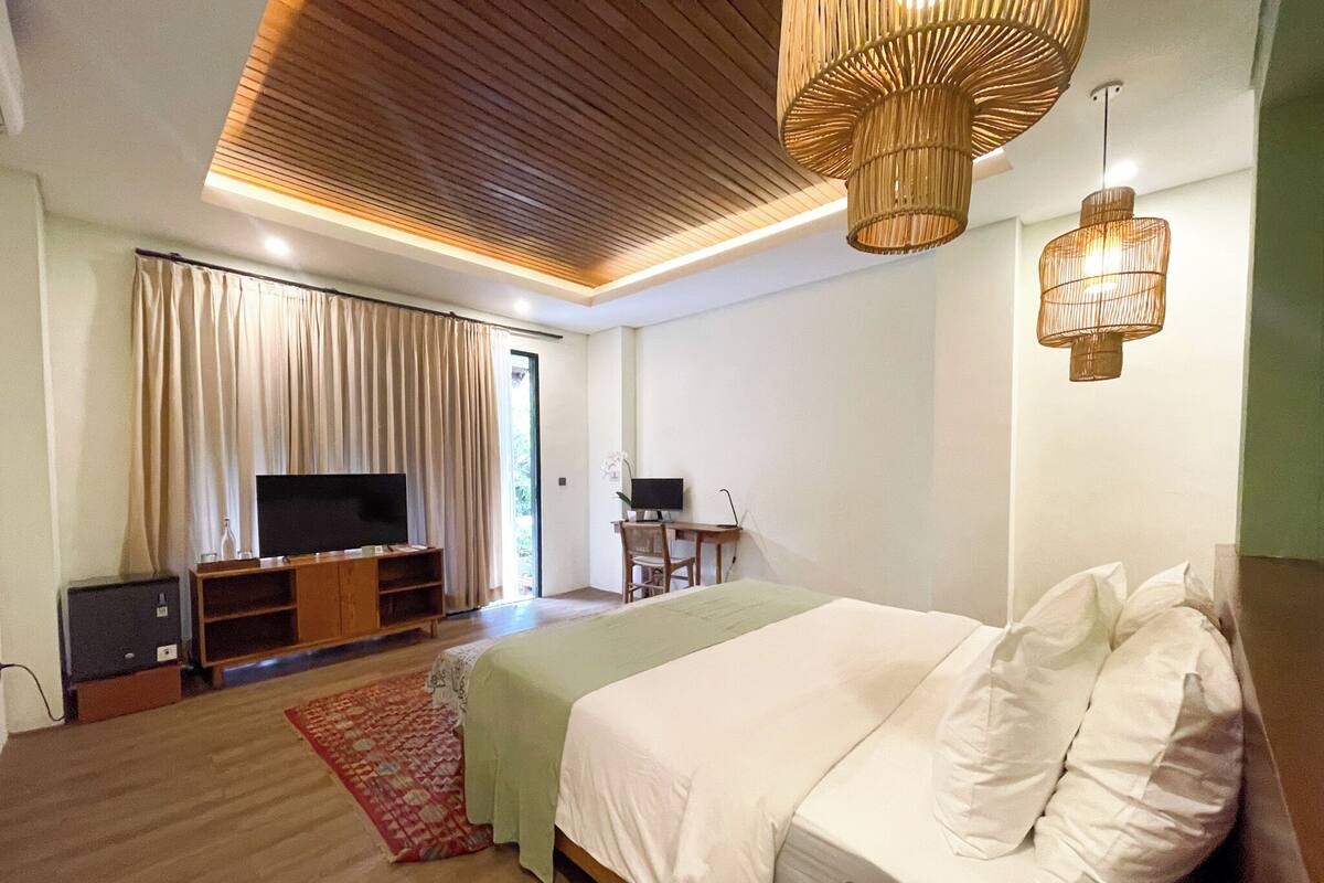 A bedroom with a bed, a TV, a desk, and a chair.