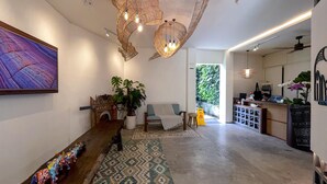 A modern interior with a wooden bench, a large abstract painting, and a reception desk with a computer. - Leafy Home Canggu (Canggu)