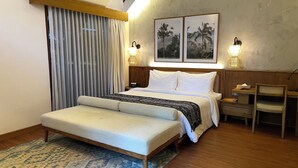 A hotel room with a large bed, a bench, a desk, and two wall-mounted lamps. - Leafy Home Canggu (Canggu)