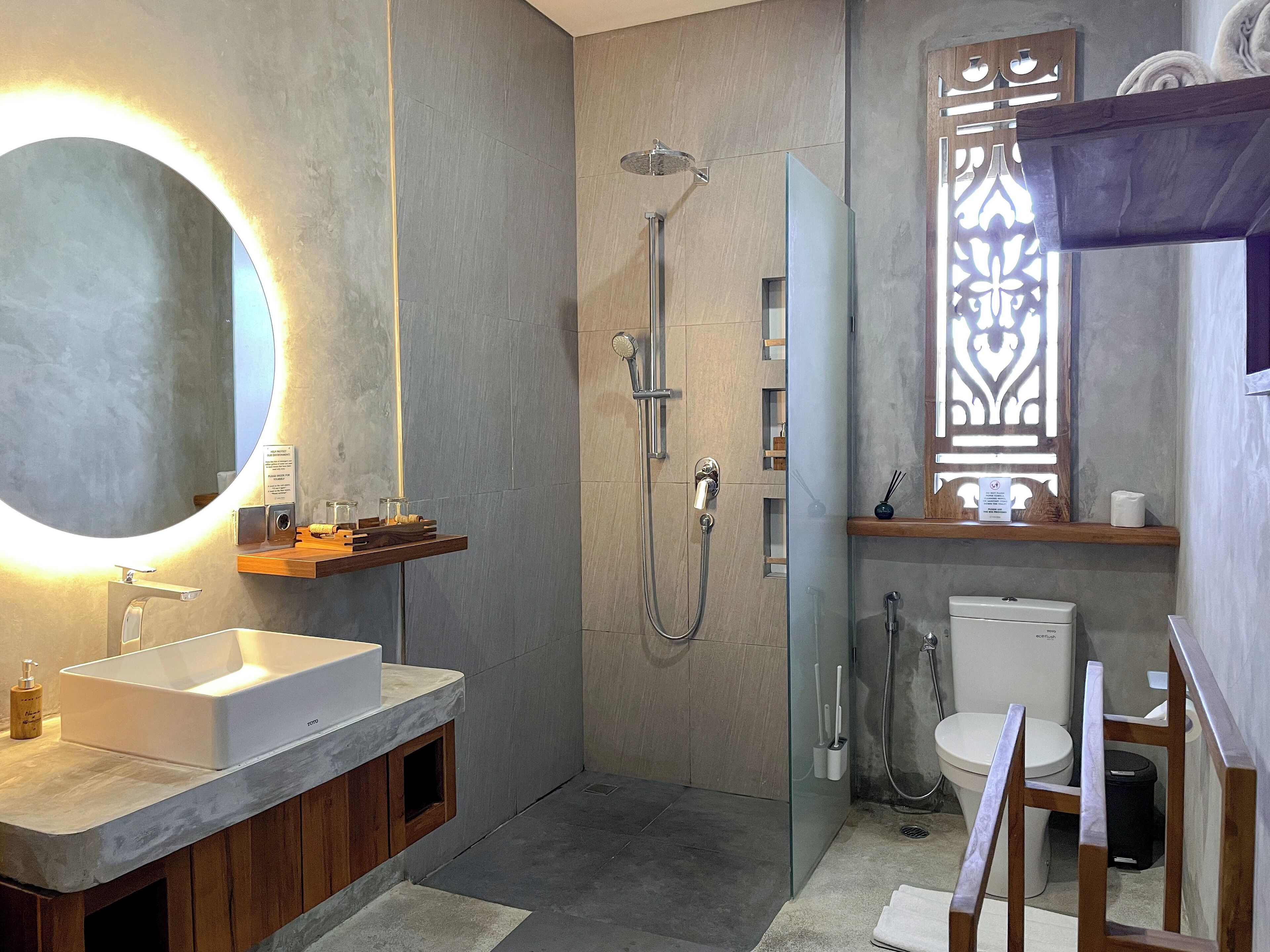 Un baño moderno con un espejo grande, ducha e inodoro.