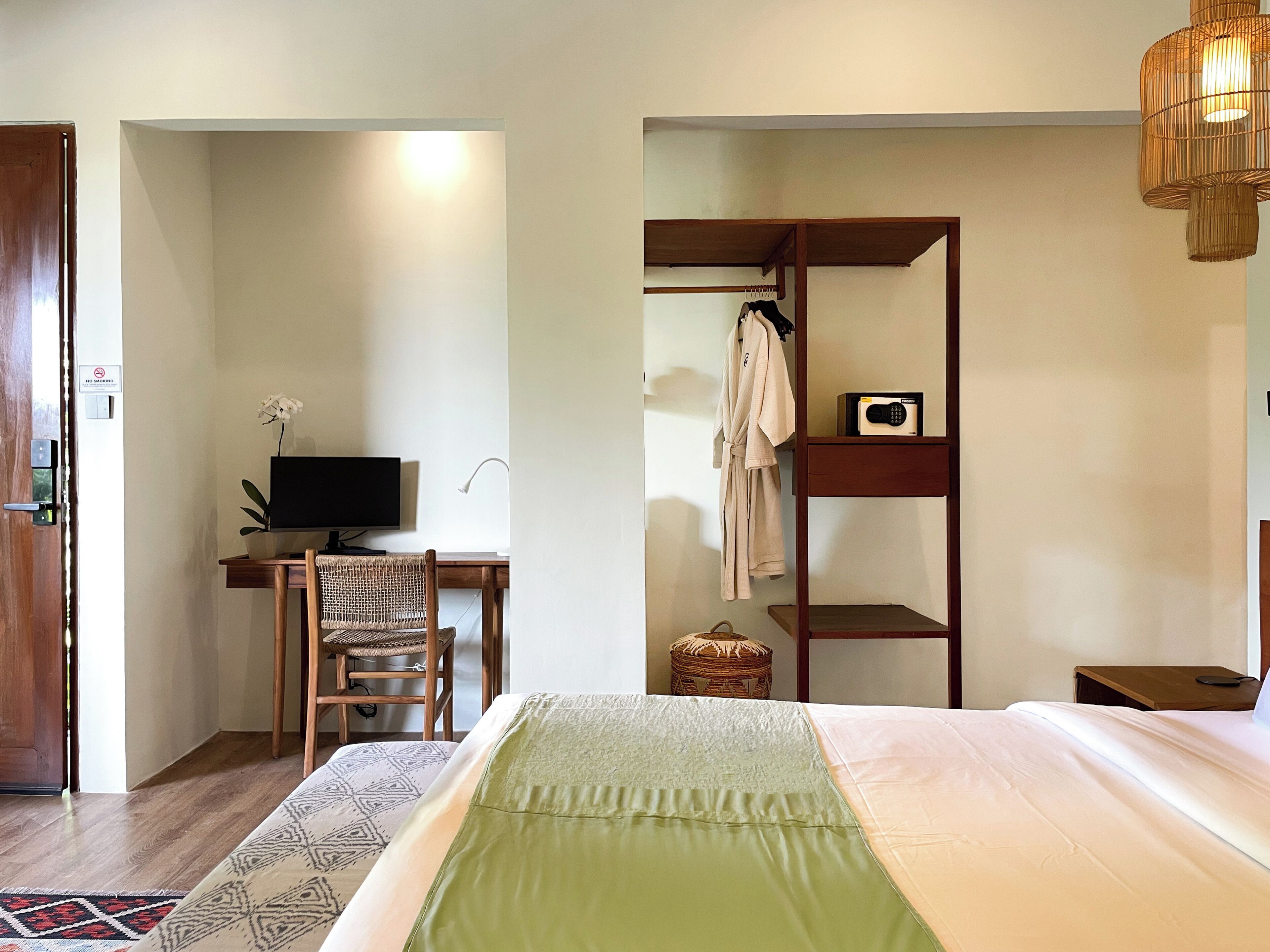 Een kamer met een bed, een bureau met een computer, een stoel, een kledingkast en een televisie.
