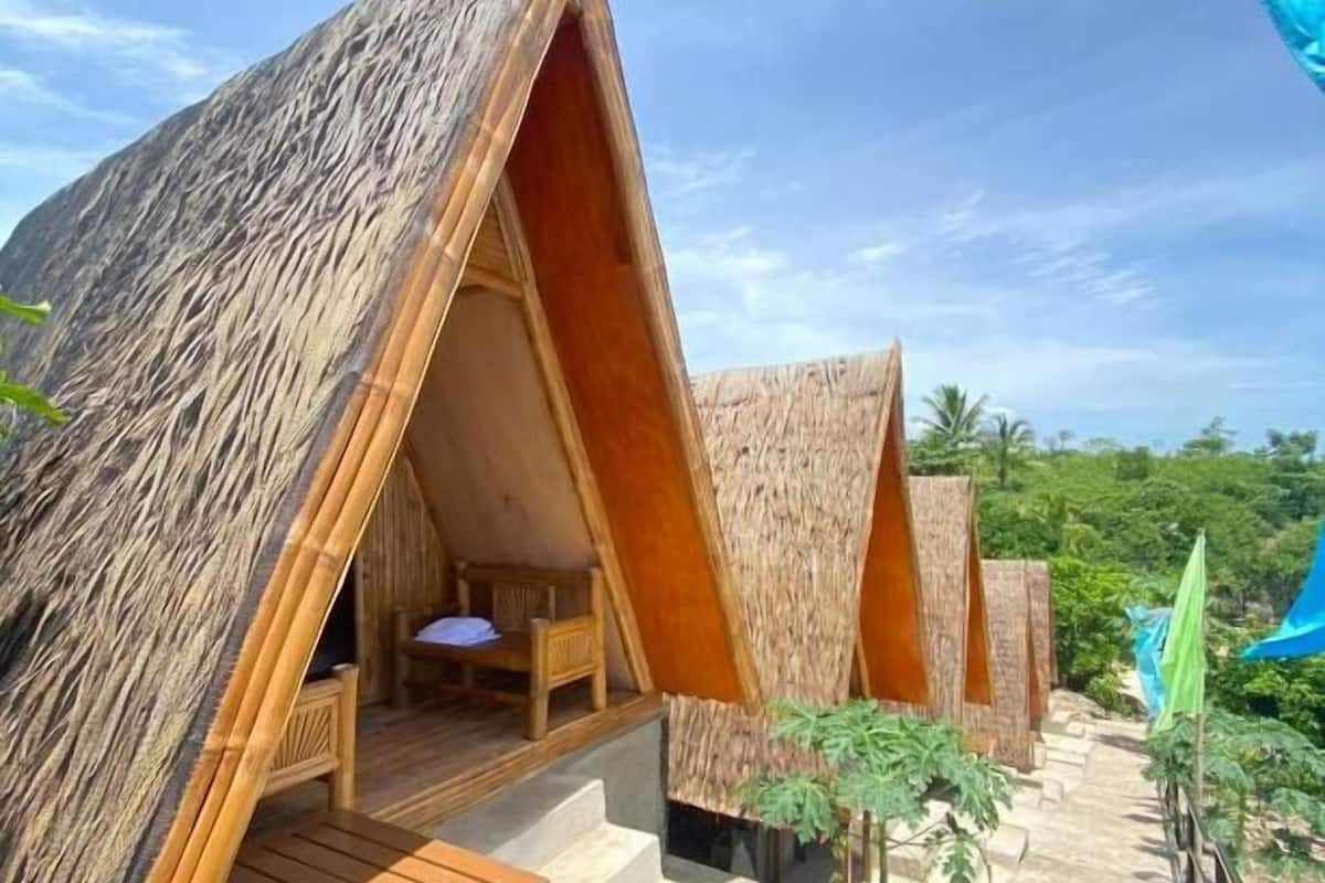 Conjunto de alojamientos tipo cabaña, con fachada de madera, mobiliario exterior y vistas despejadas del paisaje circundante.