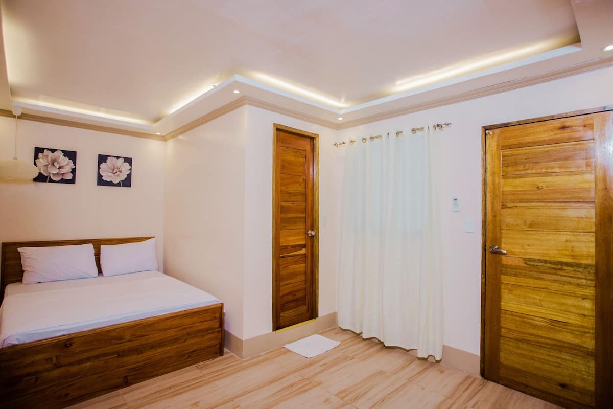 Un dormitorio con cama y puerta de madera, y una cortina blanca.