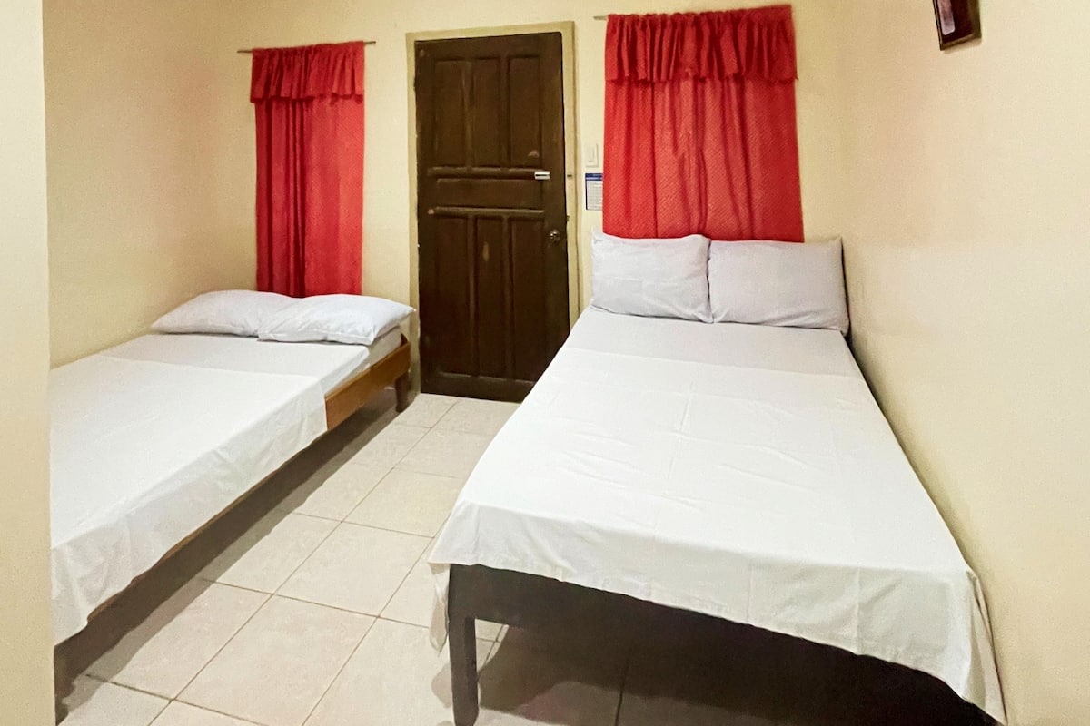 Una habitación con dos camas individuales, una mesa de madera y una puerta.