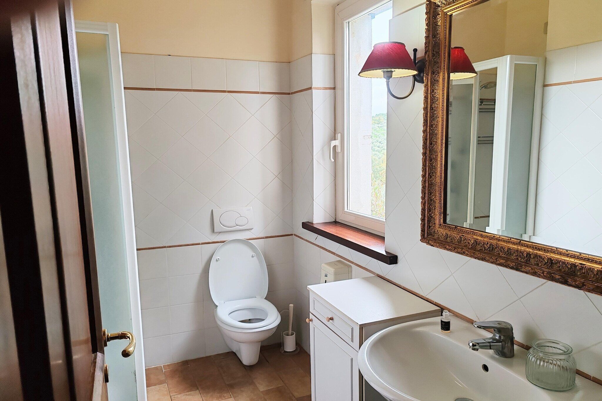 Une salle de bain avec des toilettes, un lavabo et un miroir.