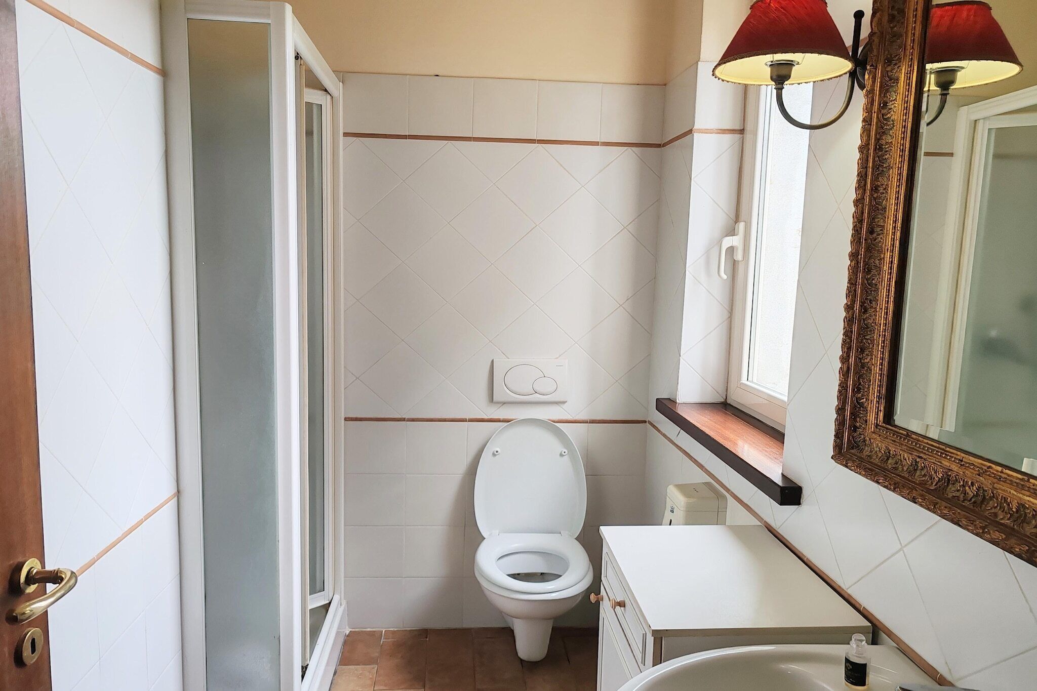 A bathroom with a toilet, sink, and mirror.